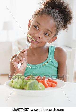 Stock Photo - Mixed race girl eating healthy meal. Fotosearch