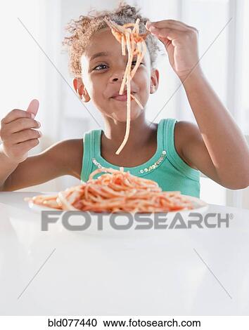Stock Image - Mixed race girl eating spaghetti. Fotosearch