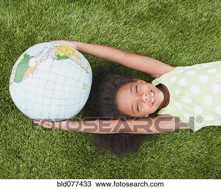 Stock Image - Mixed race girl holding globe. Fotosearch