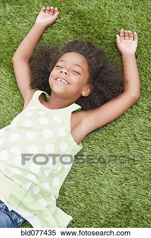 Mixed race girl laying in grass View Large Photo Image Stock Photography - Mixed race girl laying in grass. Fotosearch