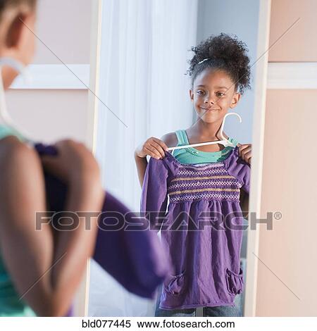 Mixed race girl looking at shirt View Large Photo Image Stock Photography - Mixed race girl looking at shirt. Fotosearch