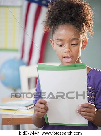Stock Photo - Mixed race girl reading report at school. Fotosearch