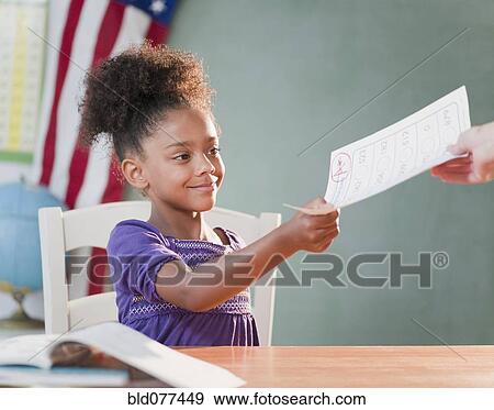 Stock Photo - Mixed race girl receiving schoolwork from teacher. Fotosearch