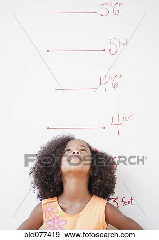 Mixed race girl standing near height chart View Large Photo Image Stock Photo - Mixed race girl standing near height chart. Fotosearch