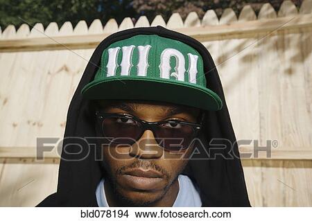 Picture - African American man in sunglasses, cap and hoodie. Fotosearch