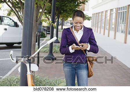 African American woman text messaging on cell phone View Large Photo Image Stock Photo - African American woman text messaging on cell phone. Fotosearch