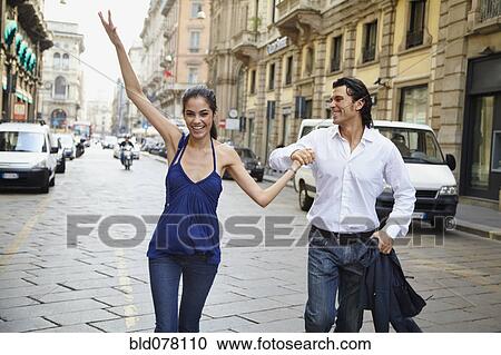 Stock Image - Couple holding hands in street. Fotosearch
