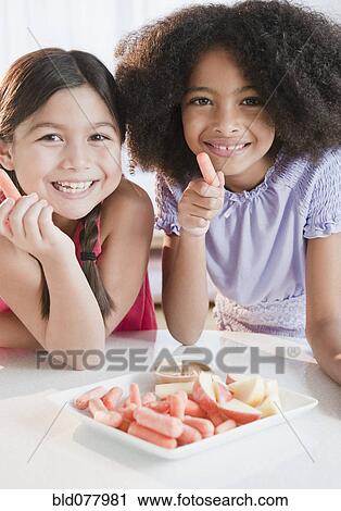 Stock Image - Girls eating fruits and vegetables for snack. Fotosearch