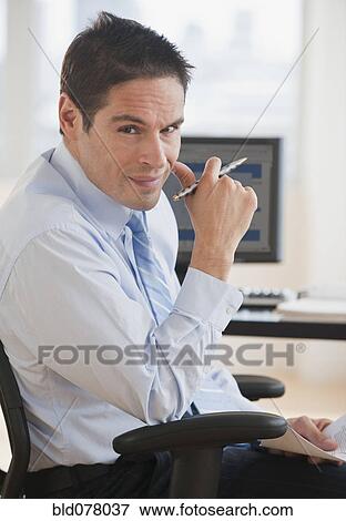 Stock Photo - Hispanic businessman sitting at desk. Fotosearch