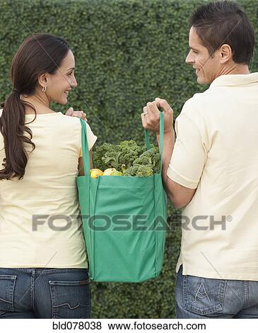 Stock Photo - Hispanic couple carrying reusable grocery bag. Fotosearch