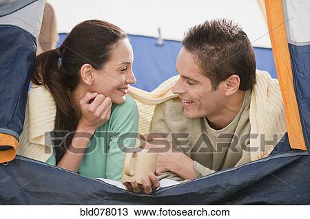 Stock Image - Hispanic couple laying in tent. Fotosearch