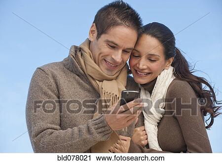 Hispanic couple looking at cell phone View Large Photo Image Stock Image - Hispanic couple looking at cell phone. Fotosearch