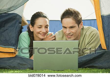 Picture - Hispanic couple using laptop in tent. Fotosearch