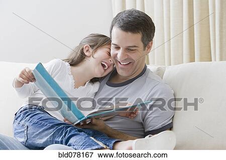 Stock Photo - Hispanic father reading book to daughter. Fotosearch