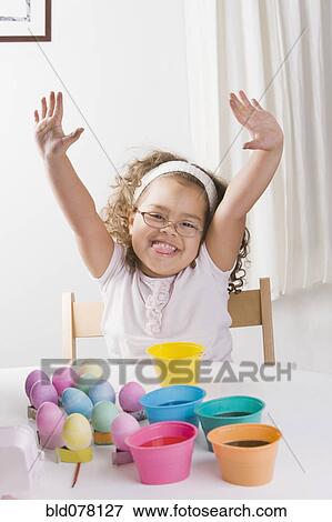 Stock Photo - Hispanic girl decorating Easter eggs. Fotosearch