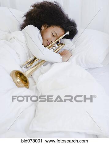 Stock Image - Hispanic girl sleeping with trumpet. Fotosearch