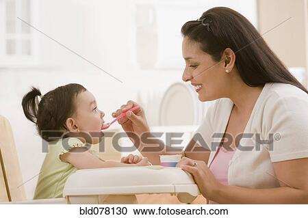 Hispanic mother feeding young daughter View Large Photo Image Stock Image - Hispanic mother feeding young daughter. Fotosearch