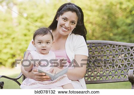 Stock Image - Hispanic mother reading to daughter. Fotosearch