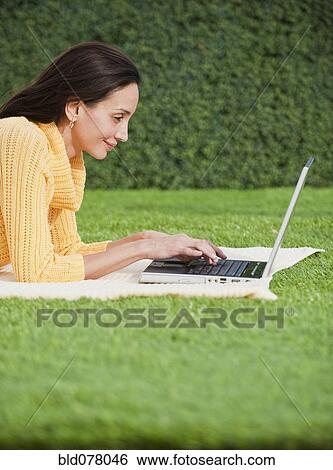 Hispanic woman using laptop in park View Large Photo Image Stock Photograph - Hispanic woman using laptop in park. Fotosearch