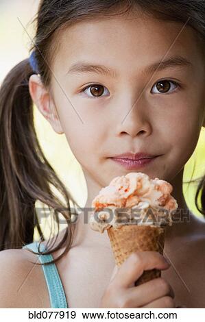 Mixed race girl eating ice cream cone View Large Photo Image Stock Photo - Mixed race girl eating ice cream cone. Fotosearch