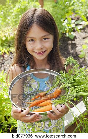 Stock Photograph - Mixed race girl holding carrots. Fotosearch