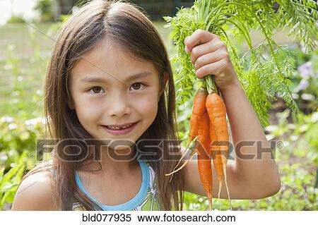 Stock Photography - Mixed race girl holding carrots. Fotosearch