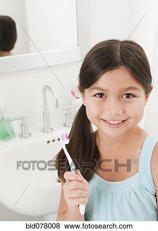 Stock Photo - Mixed race girl holding toothbrush. Fotosearch