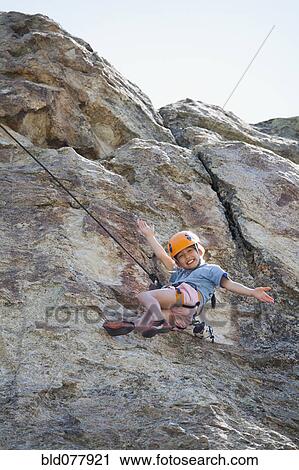 Stock Image - Mixed race girl rock climbing. Fotosearch