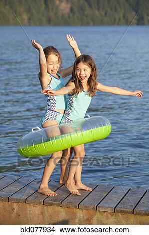 Picture - Mixed race sisters playing on pier. Fotosearch