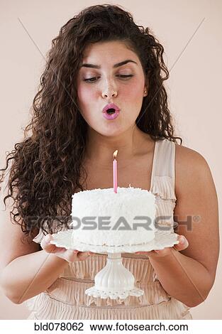 Mixed race woman blowing out candle on birthday cake View Large Photo Image Stock Image - Mixed race woman blowing out candle on birthday cake. Fotosearch