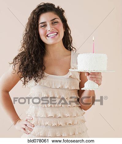 Stock Image - Mixed race woman holding birthday cake. Fotosearch