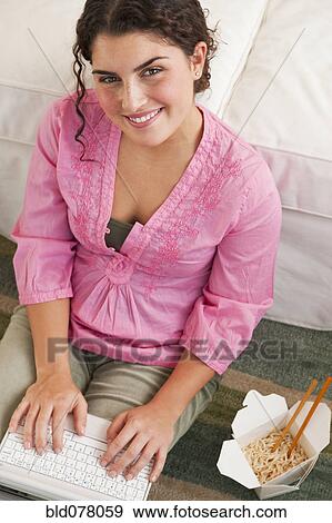 Mixed race woman using laptop and eating take-out View Large Photo Image Stock Photo - Mixed race woman using laptop and eating take-out. Fotosearch