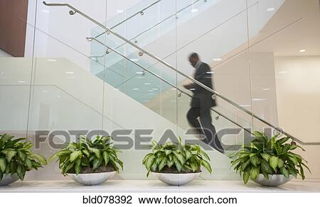 Stock Image - African American businessman ascending staircase. Fotosearch