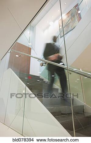 Picture - African American businessman descending staircase. Fotosearch
