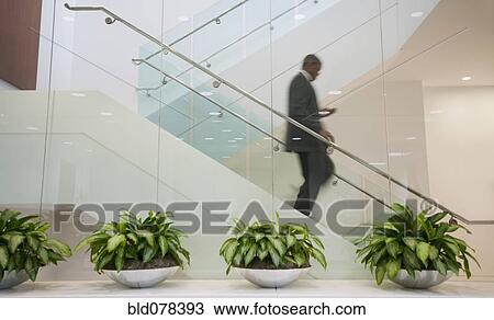 Stock Image - African American businessman descending staircase. Fotosearch