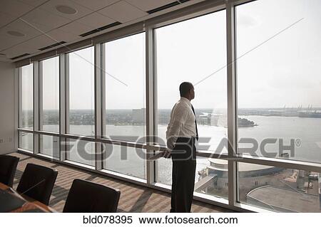 African American businessman looking out office window View Large Photo Image Stock Photography - African American businessman looking out office window. Fotosearch