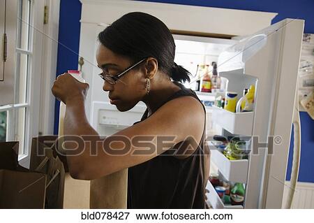 African woman unloading groceries in kitchen View Large Photo Image Stock Photo - African woman unloading groceries in kitchen. Fotosearch