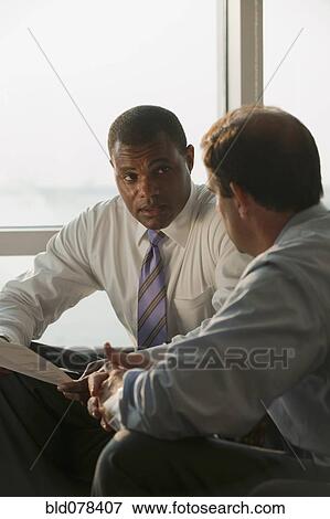 Stock Photo - Businessmen having meeting in office. Fotosearch