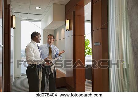 Picture - Businessmen talking in office corridor. Fotosearch