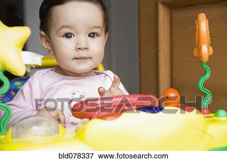 Stock Photo - Hispanic baby girl playing with toy. Fotosearch