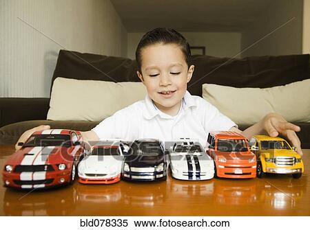 Hispanic boy lining up toy cars View Large Photo Image Stock Photography - Hispanic boy lining up toy cars. Fotosearch