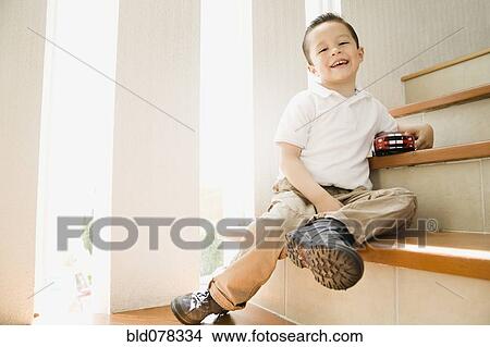 Hispanic boy sitting on staircase with toy car View Large Photo Image Picture - Hispanic boy sitting on staircase with toy car. Fotosearch