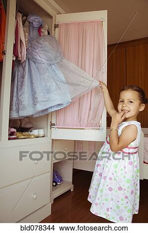 Picture - Hispanic girl taking costume from closet. Fotosearch