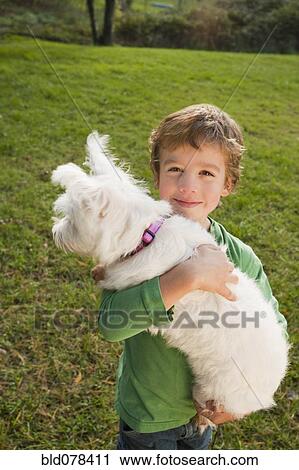 Stock Image - Mixed race boy holding small dog. Fotosearch
