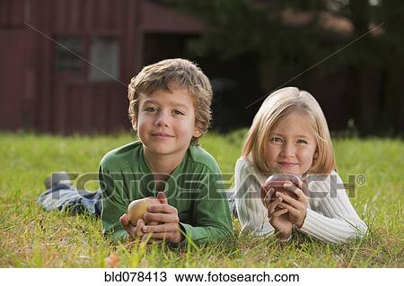 Stock Image - Mixed race brother and sister laying in grass. Fotosearch