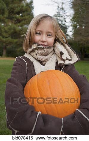 Stock Photography - Mixed race girl holding pumpkin. Fotosearch
