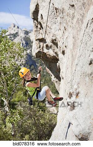Stock Photograph - Mixed race girl rock climbing. Fotosearch