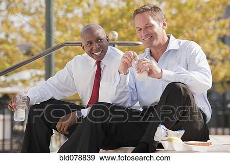 Stock Photo - Businessmen eating lunch on steps. Fotosearch