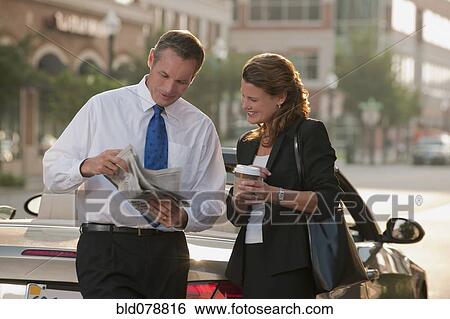 Stock Photograph - Caucasian business people looking at newspaper. Fotosearch