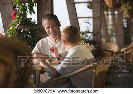 Picture - Caucasian father and son eating in restaurant. Fotosearch
